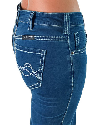Close-up of a person wearing blue denim jeans, showing the back pocket area with white contrast stitching and a visible TUFF brand patch on the pocket.