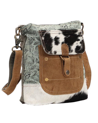 Handbag with cowhide pattern and floral design on a white background