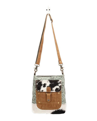 Crossbody bag with cowhide pattern on a white background