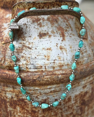 Turquoise beaded bracelet on a rustic metal surface
