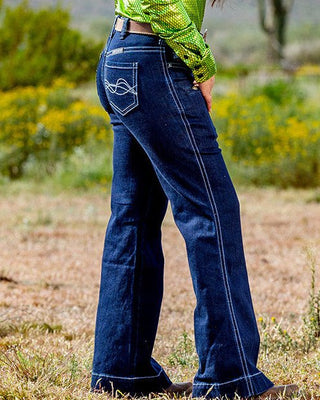 Woman in a green shirt and cowboy hat standing in a desert landscape
