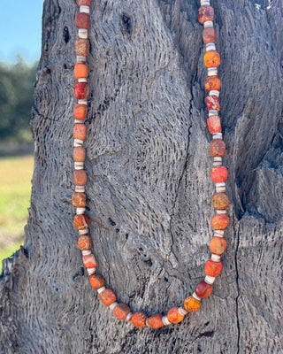 Necklace with orange and white beads on a textured surface