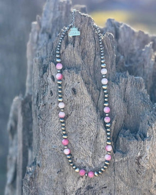 Necklace with pink and black beads on a wooden surface