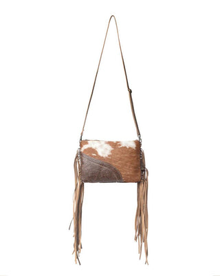 Brown and white cowhide leather handbag with fringes on a white background