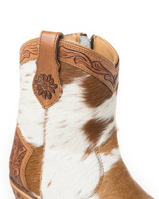 Close-up of a brown and white cowhide boot with intricate leatherwork on a white background