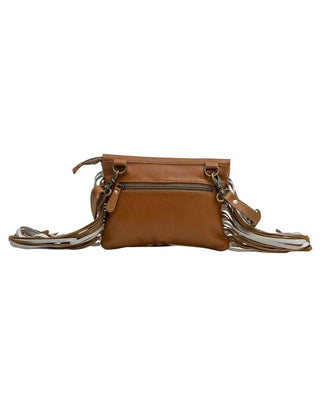 A brown leather crossbody bag with a front zip pocket and a long, fringed strap in brown, beige, and white, shown against a plain white background.