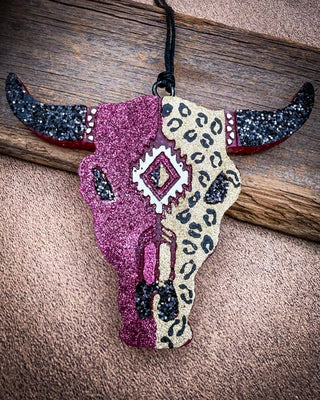 Maroon and leopard bull skull car freshie laying on wood