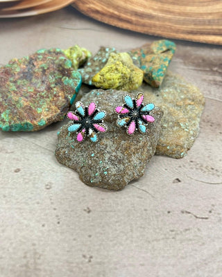 Pair of earrings with pink and blue floral design on a stone surface