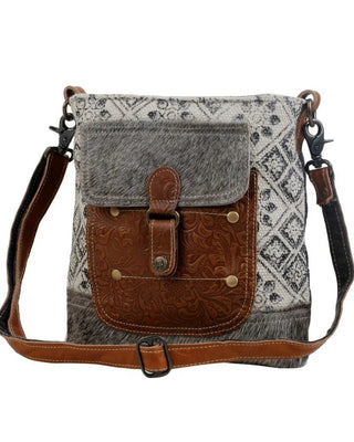 Crossbody bag with patterned flap and brown accents on a white background