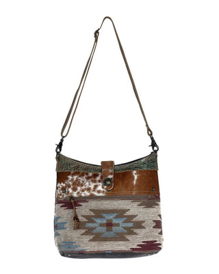 Multicolored patterned handbag with brown leather accents on a white background
