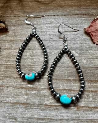 Pair of beaded earrings with turquoise beads on a wooden surface