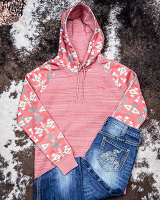 Pink hoodie with floral sleeves and blue jeans on a textured surface