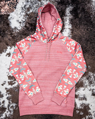 Pink hoodie with geometric pattern on sleeves against a textured brown background