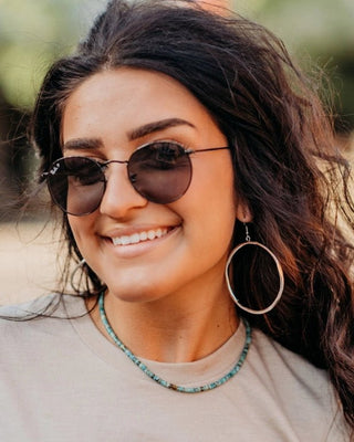 Woman wearing sunglasses and a necklace with a blurred background