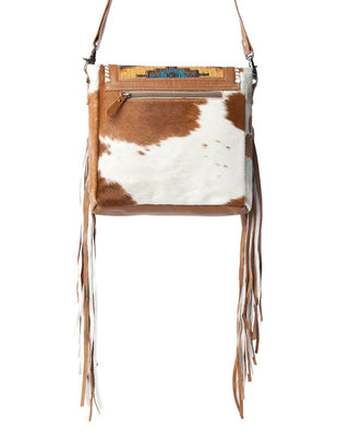 Brown and white cowhide bag with fringe on a white background