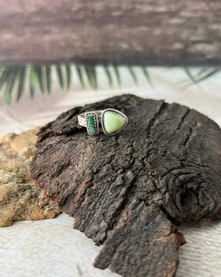 Silver ring with a green stone on a textured surface