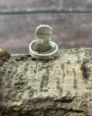 Silver ring with engraved text on a wooden surface