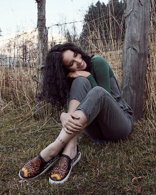Woman sitting against a wooden post in a natural setting