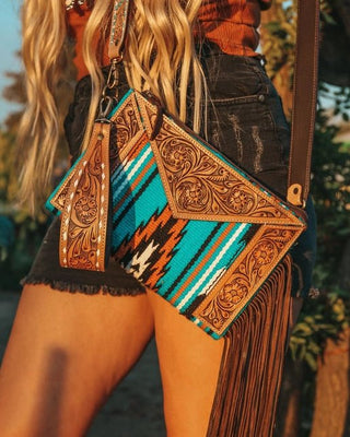 Person holding a decorative handbag with fringe details outdoors