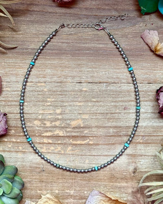 Necklace with beads on a wooden surface with dried flowers and plants