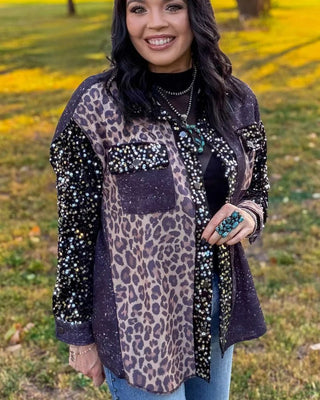 A woman wearing a mixed-media jacket with leopard print, black sequined sleeves, and a dark purple pocket, standing outdoors in a grassy park area.