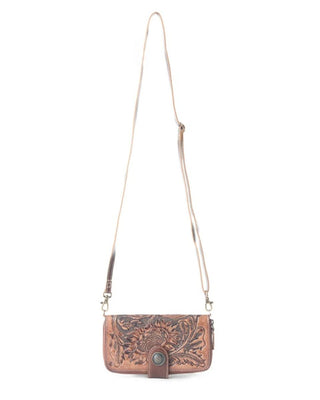 A brown tooled leather crossbody bag with an intricate floral design, a long adjustable strap, and a snap closure, shown against a plain white background.